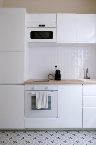 Il comprend une cuisine blanche équipée d'une cuisinière et d'un four micro-ondes. dans l'établissement Villa Jeanne - Confort et plage, au Tréport