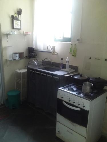 uma cozinha com um fogão e um lavatório em Pousada do Alex em Campos dos Goytacazes
