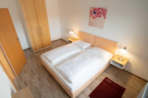 - une petite chambre avec un lit blanc et deux lampes dans l'établissement Family XL - Ferienwohnungen, à Lutzmannsburg