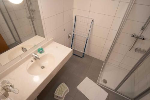 a white bathroom with a sink and a shower at Family XL - Ferienwohnungen in Lutzmannsburg