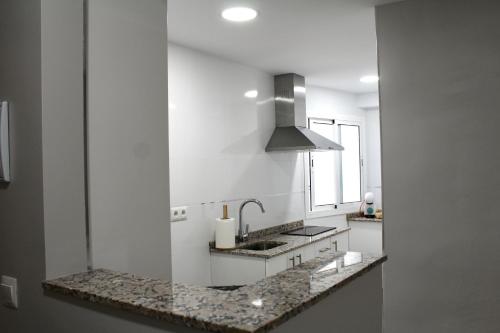 uma cozinha branca com um lavatório e um fogão em WISH SUITE BASILICA em Sevilha