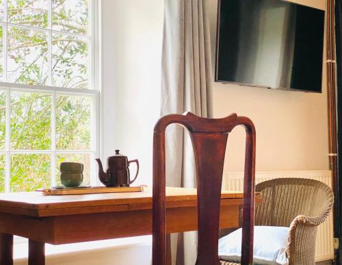 a wooden table with a chair next to a window at The Garden Room Apartment in Cardigan
