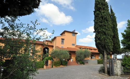 un gran edificio de naranjos con árboles delante de él en Hotel Hermitage, en Poggio a Caiano