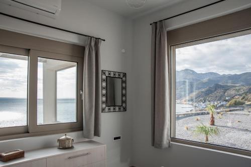 a room with two windows with a view of the beach at Evgoro - Infinite View in Tsoútsouros