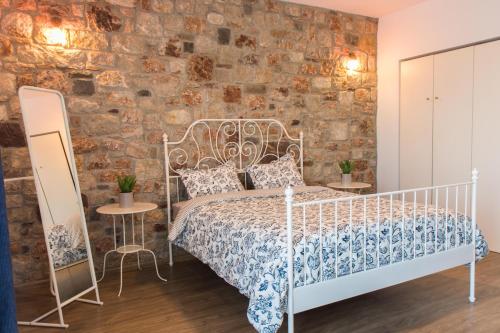 a bedroom with a white bed and a brick wall at Roccia di Isidoro in Áyios Isídhoros