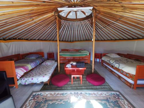 une chambre avec 3 lits et une table dans une tente dans l'établissement Aux Yourtes de La Fabrique, à Saint-Florent-des-Bois