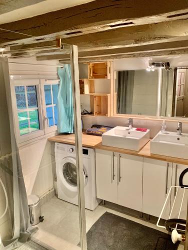 une salle de bain avec deux lavabos et une machine à laver dans l'établissement Gîte à la ferme de Sainte Radegonde, à Lanneray