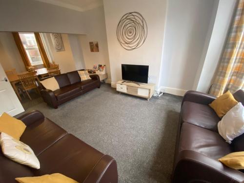 Sala de estar con 2 sofás de cuero y TV en Blackpool Abode - Palatine House en Blackpool