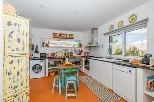 a kitchen with white cabinets and a table and chairs at Villa Nova in Comporta
