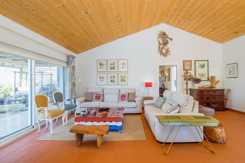 a living room with white furniture and a wooden ceiling at Villa Nova in Comporta