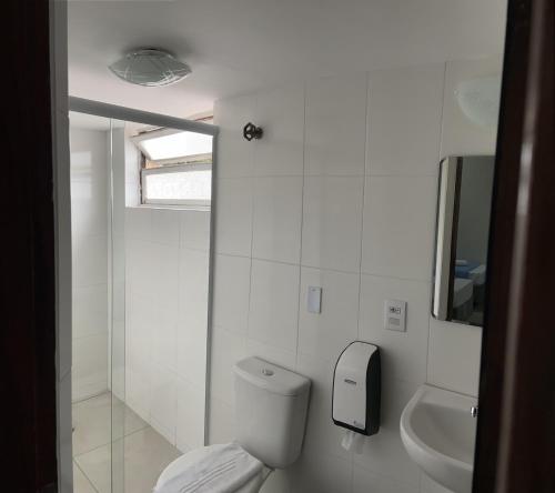 a white bathroom with a toilet and a sink at Pousada Albamar Guarujá in Guarujá