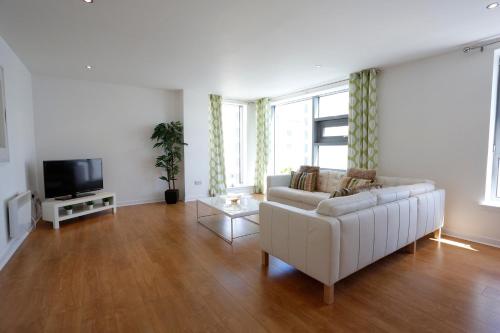 a living room with a white couch and a tv at Edinburgh Waterfront Apartments in Edinburgh