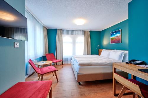 ein Hotelzimmer mit einem Bett, einem Tisch und Stühlen in der Unterkunft 5th Floor Basic Rooms - shared bathrooms in Interlaken