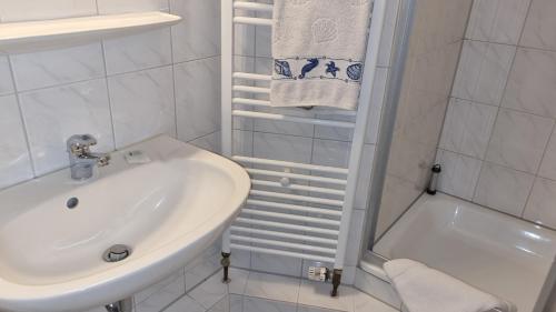 ボルクムにあるHaus Borkumitte Appartement Freyaの洗面台とバスタブのある白いバスルーム