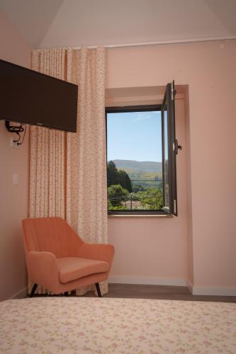 a living room with a chair and a window at Casa da Mela in Gouveia