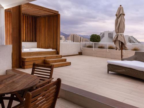 a rooftop patio with a tub and a table and chairs at King Solomon by Isrotel Collection in Eilat