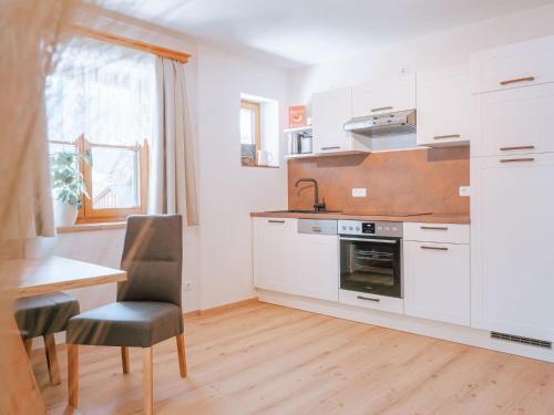 cocina con armarios blancos, mesa y fogones en Apartment Haus Toplitzsee nahe dem Grundlsee und Toplitzsee, en Gössl