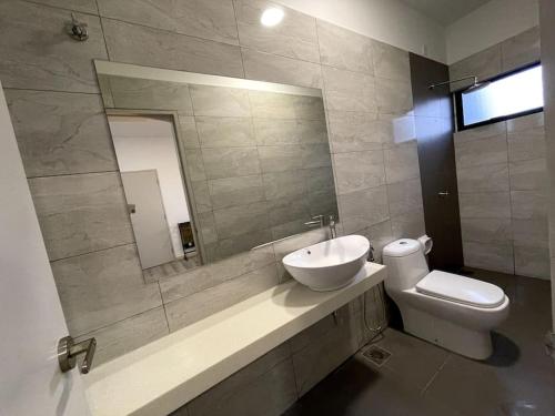 a bathroom with a sink and a toilet and a mirror at Five BEDROOMS RESIDENTIAL HOME WITH FREE WIFI in Sepang