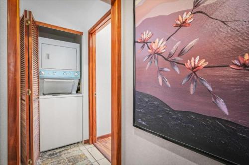 a kitchen with a painting of flowers on the wall at Kahaluu Bay Village 201 by Casago Kona - Snorkeling, Surfing and Spaciousness in Kailua-Kona