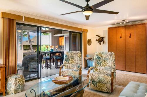 ein Wohnzimmer mit Stühlen und einem Glastisch in der Unterkunft Spacious & Inviting Kanaloa #3503 by Casago Kona - Come Play in Kailua-Kona