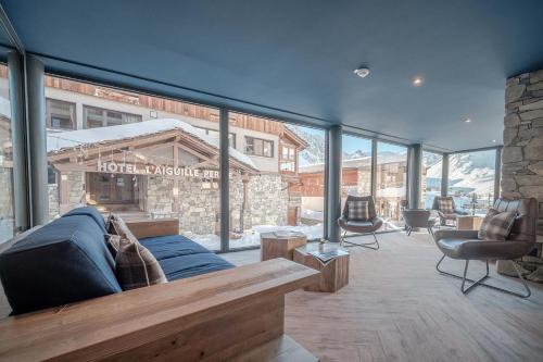 a living room with a blue couch and some windows at Residence Denali by Alpapart in Tignes