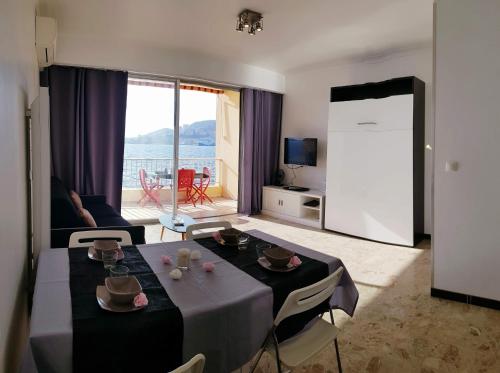un salon avec une table avec des chaises et un salon dans l'établissement Sudio bord de mer Ajaccio, à Ajaccio