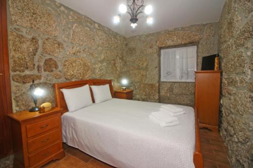 a bedroom with a bed and a stone wall at Eira Costa House by Gerês Casas in Geres