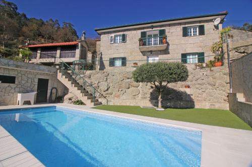 a house with a swimming pool in front of a building at Eira Costa House by Gerês Casas in Geres