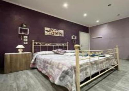 1 dormitorio con cama y pared púrpura en Casa Vacanza GLICINE, en Venaria Reale
