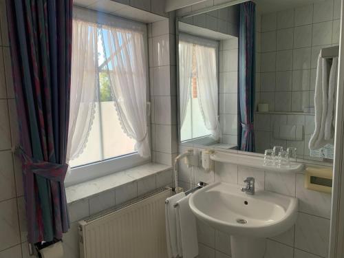 ein Bad mit einem Waschbecken, einem Spiegel und einem Fenster in der Unterkunft Hotel Flora in Herzlake