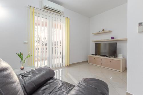 een woonkamer met een bank en een televisie bij Koraca B4 in Krmenjak