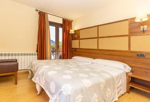 a bedroom with a large bed and a large window at Hotel Solana in Benasque