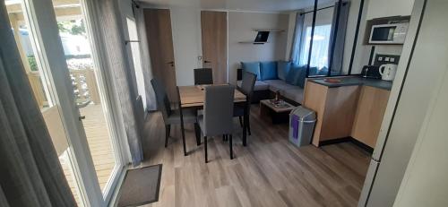 a room with a table and a kitchen and a dining room at Mobil-home de charme dans les Landes, neuf, tout équipé in Gastes