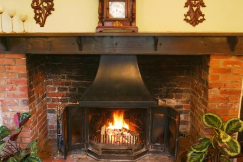 a fireplace with a clock on top of it at Bridge Farmhouse - Eight ensuite bedrooms in Salisbury