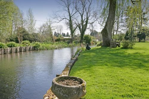 a river in a park next to a grass field at Bridge Farmhouse - Eight ensuite bedrooms in Salisbury