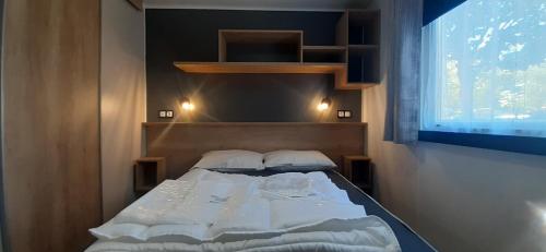 1 dormitorio con 1 cama en una habitación con ventana en Mobil-home de charme dans les Landes, neuf, tout équipé, en Gastes