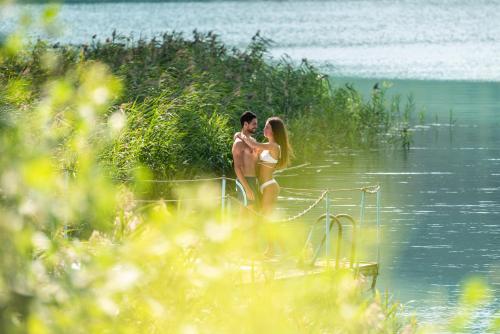 Ein Mann und eine Frau stehen im Wasser in der Unterkunft Panoramic Hotel San Carlo Ledro in Ledro