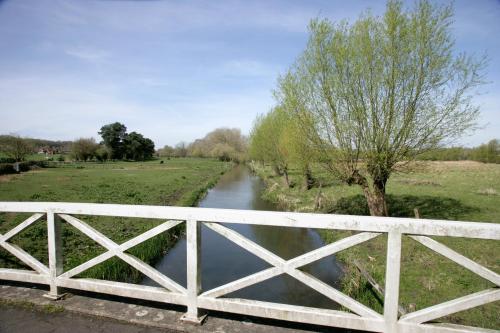 a white bridge over a river next to a field at Bridge Farmhouse - Eight ensuite bedrooms in Salisbury
