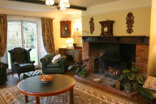 a living room with a fireplace and a table at Bridge Farmhouse - Eight ensuite bedrooms in Salisbury
