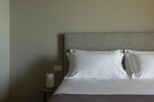 a bed with white pillows and a candle on a table at Hotel Windsor in Laigueglia