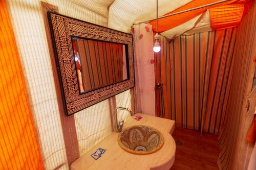 a small bathroom with a toilet and a mirror at Shooting Stars Camp in Merzouga