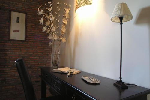 a desk with a lamp and a vase on it at Hotel Posada La Robleda in Arnuero