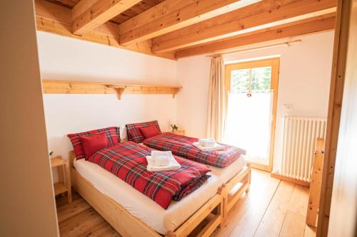 Un dormitorio con una cama con almohadas rojas y una ventana en MOIE' CAMERE en Padola