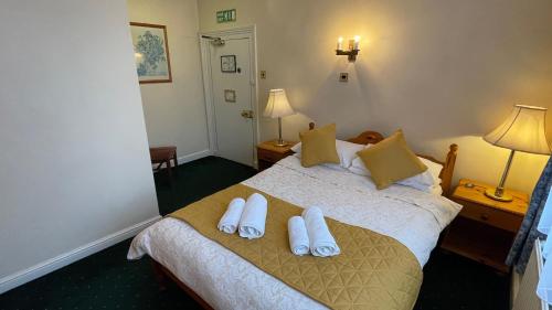 a bedroom with a bed with white slippers on it at Crown Hotel in Downham Market