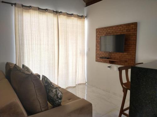 a living room with a couch and a television at Maragogi Chalés Antunes in Maragogi
