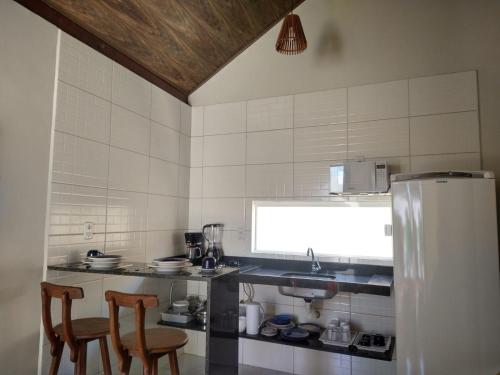 a kitchen with two chairs and a refrigerator at Maragogi Chalés Antunes in Maragogi