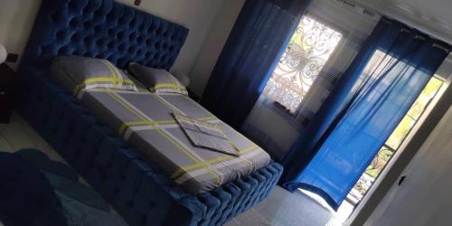- une chambre avec un lit et 2 fenêtres avec des rideaux bleus dans l'établissement Studios-Appartements meublés Makepé BM, à Douala