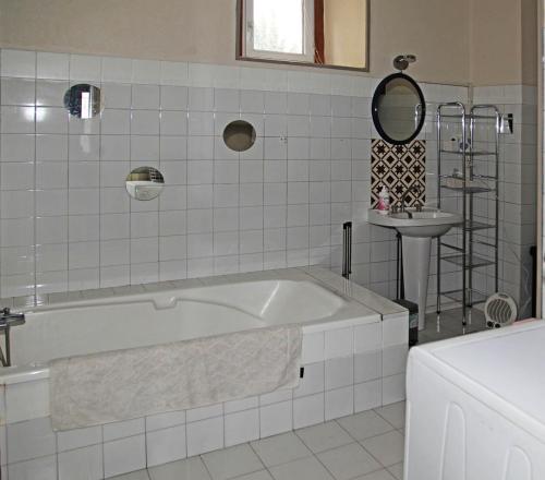 ein weißes Badezimmer mit einer Badewanne und einem Waschbecken in der Unterkunft Le Pitstop in Alan
