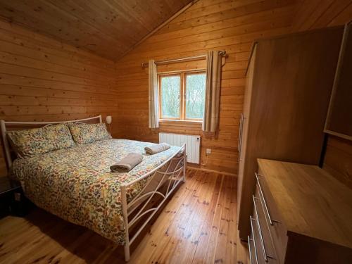 a bedroom with a bed in a wooden cabin at Kingfisher Lodge, Lake Pochard in South Cerney