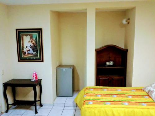 1 dormitorio con 1 cama, mesa y nevera en Apartamentos osuna, en Mazatlán